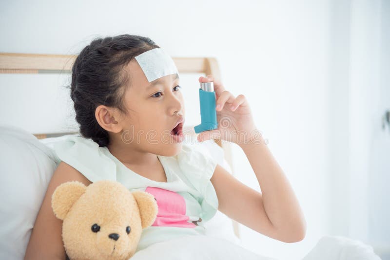 Girl sitting on bed and using broncodilator inhaler stock photos