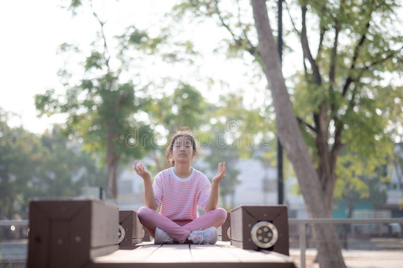 A girl is sitting on a bench in a park, meditating stock images