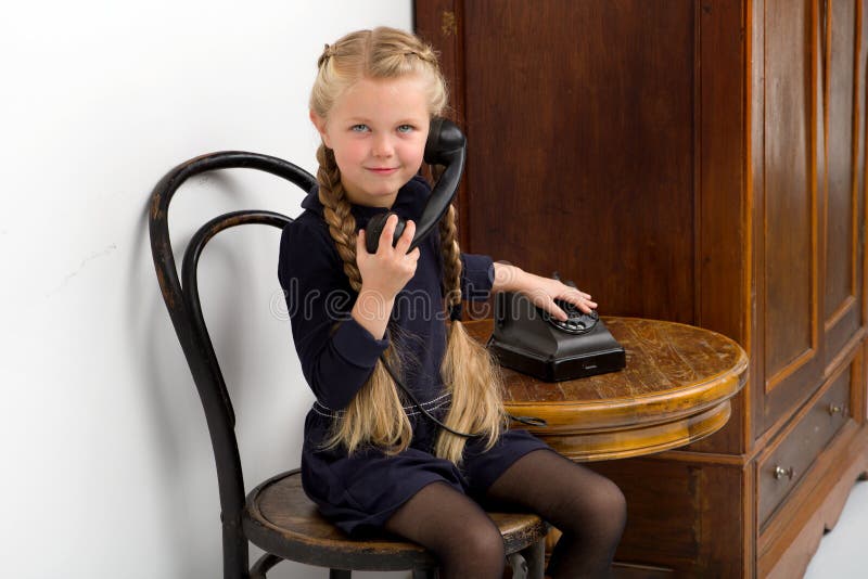 Girl sitting on chair and talking by old phone