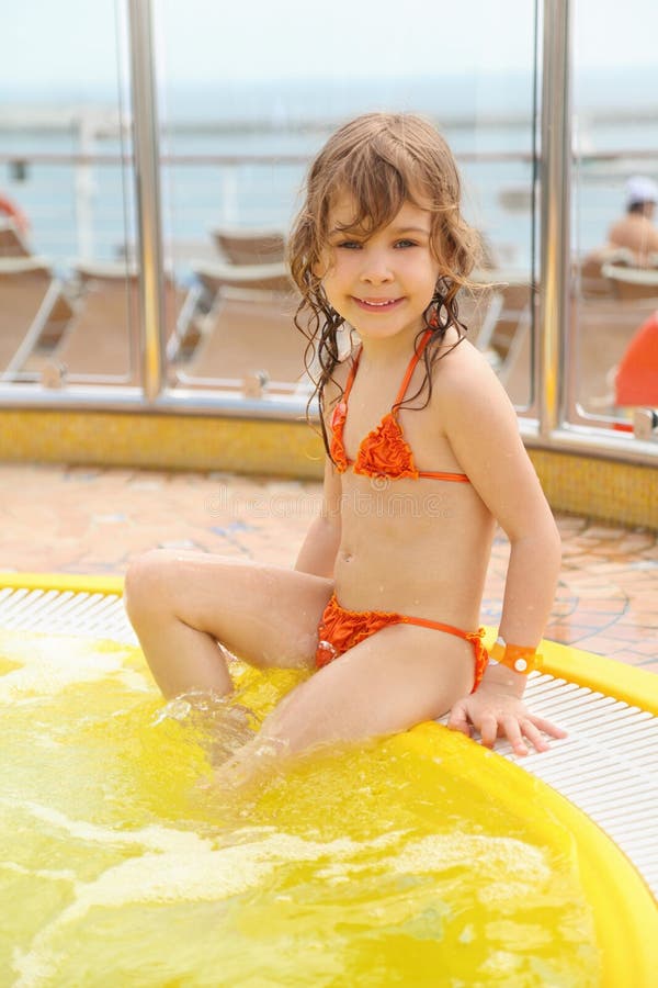 Girl sitting on edge of swimming pool