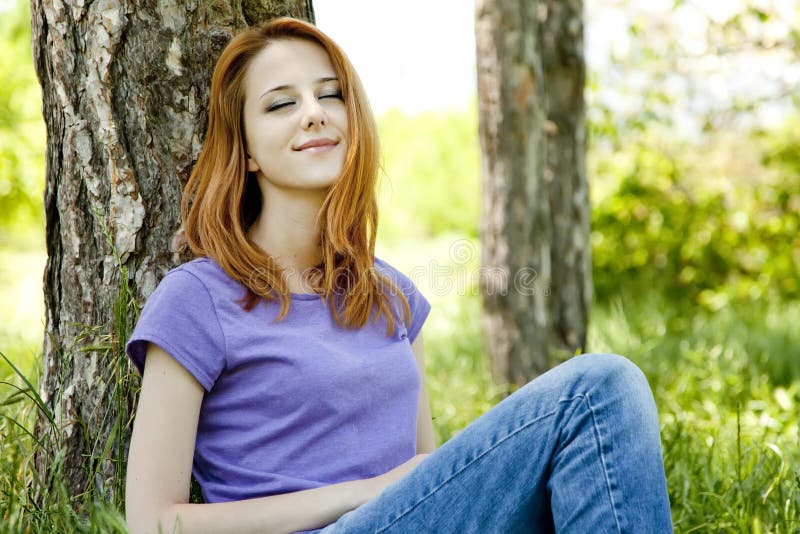 Girl sitting at green grass at park.