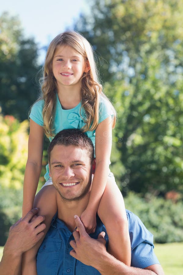 Girl sitting on her dads shoulder. 