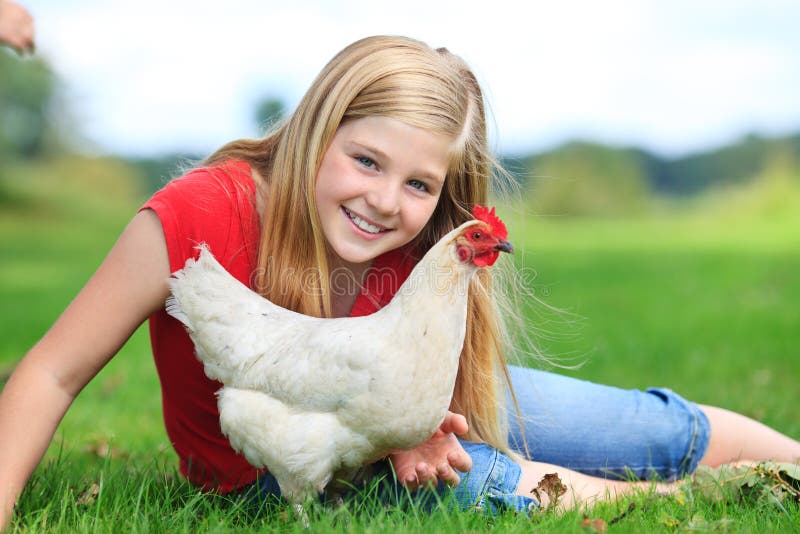 Cute girl sitting in the grass with her white chicken. Cute girl sitting in the grass with her white chicken