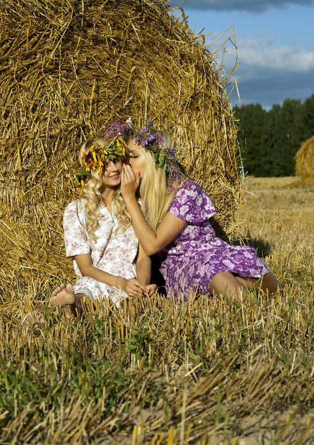 Girl sitting near a haystack in the field