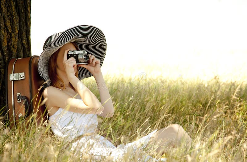 Girl sitting near tree with vintage camera.