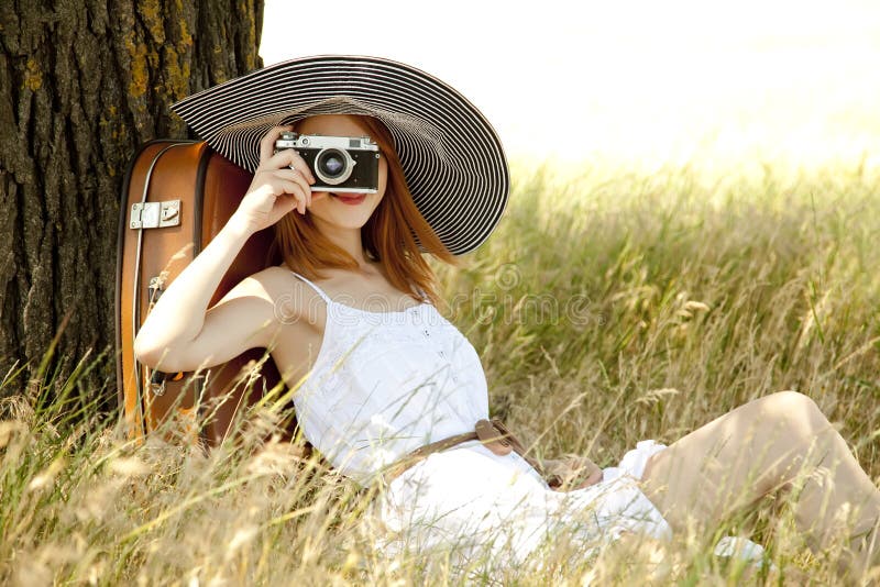 Girl sitting near tree with vintage camera.