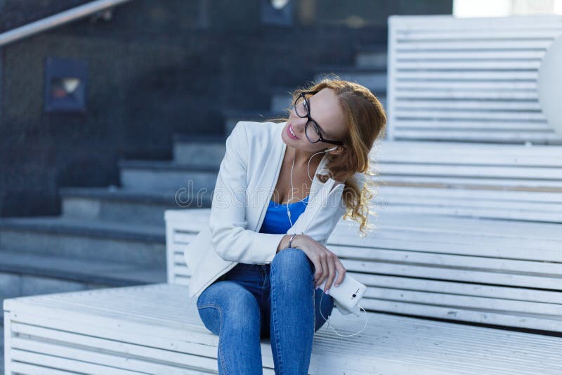 Girl sitting on the street stairs and listening to music on the phone stock photos Girl sitting on the street stairs and listening to music on the phone stock photos