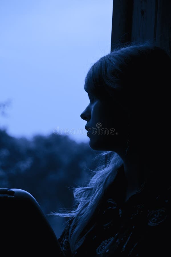 A girl sitting on window and looking outdoors