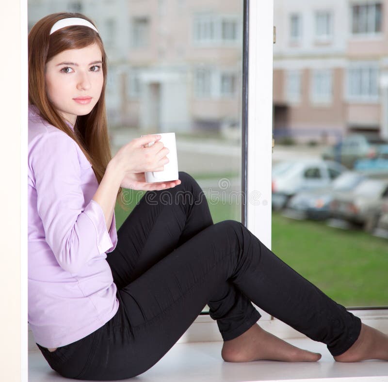 A girl is sitting on the window-sill