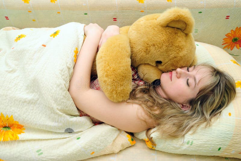 The girl sleeps with a toy bear
