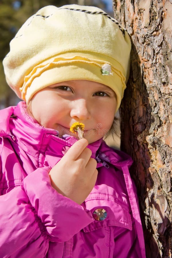 Girl smelling a yellow flower coltsfoot