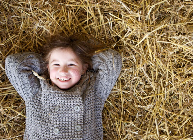 Girl smiling and lying down on hay