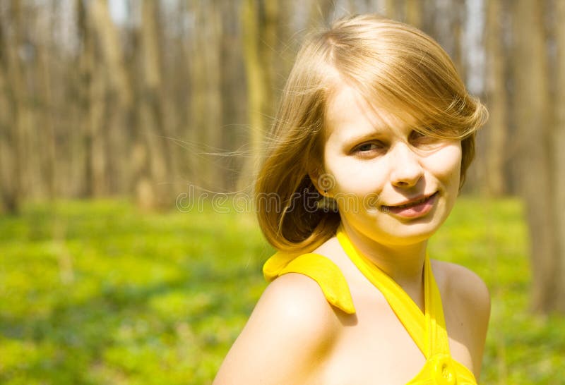 Girl smiling in sunny spring field. Copy space