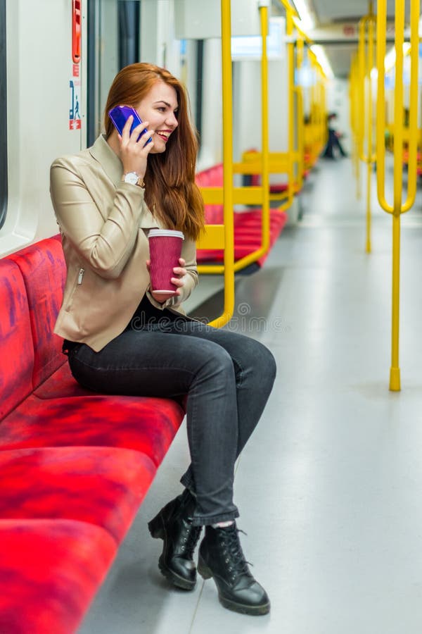 The girl speaks on a cell phone inside an empty subway train