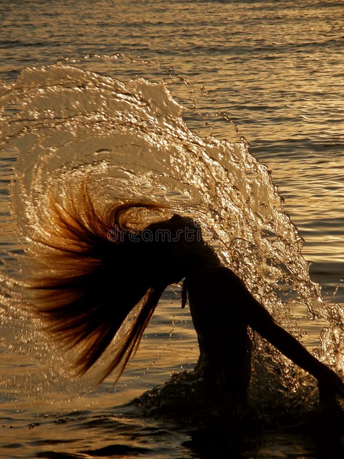 Portrait of a girl . Active young girl have a fun in water (making splash with long hair-head) at golden sunset in summer holiday Adriatic sea (Croatia-Dalmatia)- doing a water hair splash. Vertical color photo. Portrait of a girl . Active young girl have a fun in water (making splash with long hair-head) at golden sunset in summer holiday Adriatic sea (Croatia-Dalmatia)- doing a water hair splash. Vertical color photo.