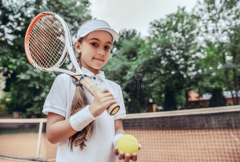 Girl sportsman with racket and ball on tennis court