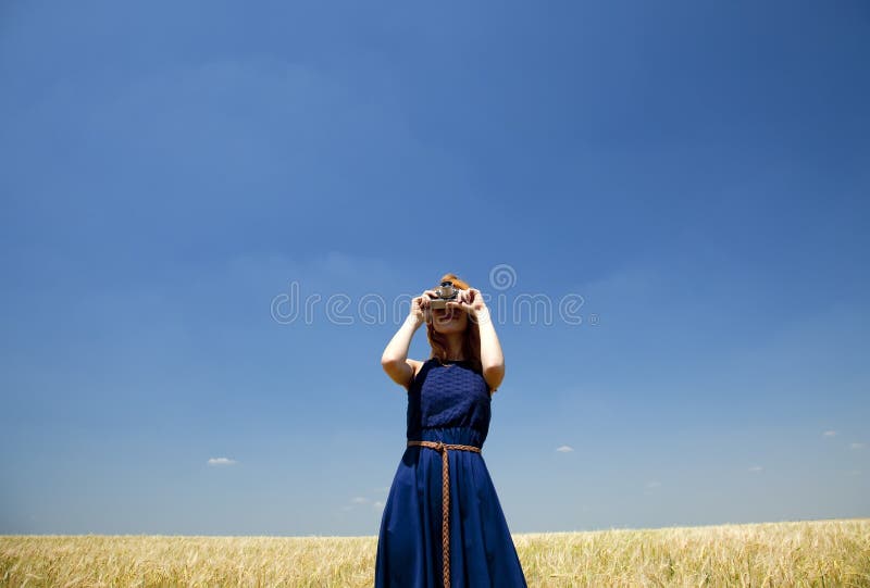 Girl at spring wheat field with retro camera.