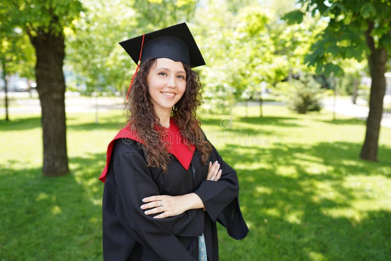 Girl is standing in green park near university. She is a graduate and in a good mood. copy space royalty free stock photo Girl is standing in green park near university. She is a graduate and in a good mood. copy space royalty free stock photo