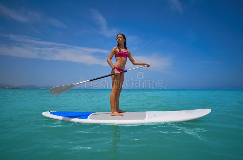 Girl standing on paddle surf board SUP
