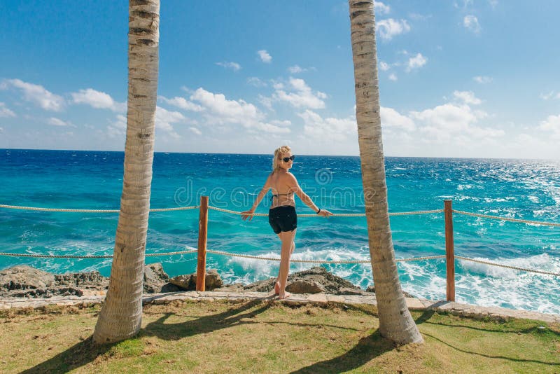 Girl Stands With Her Back Against The Blue Ocean Between Palm Trees Cancun Mexico Stock Image