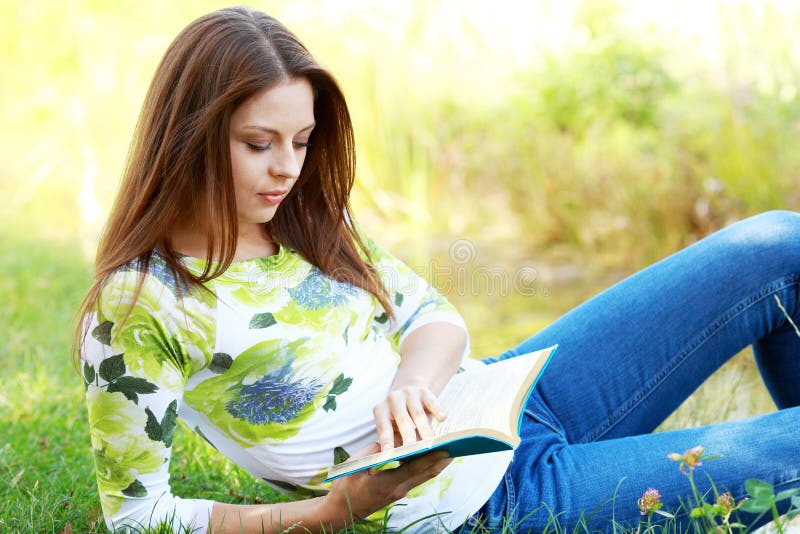 Girl student reading book in autumn park.