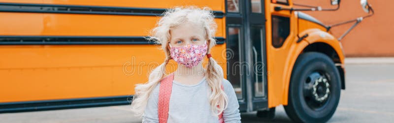 Girl student wearing face mask standing by yellow bus. Kid with personal protective equipment on face. Education and back to royalty free stock photos Girl student wearing face mask standing by yellow bus. Kid with personal protective equipment on face. Education and back to royalty free stock photos