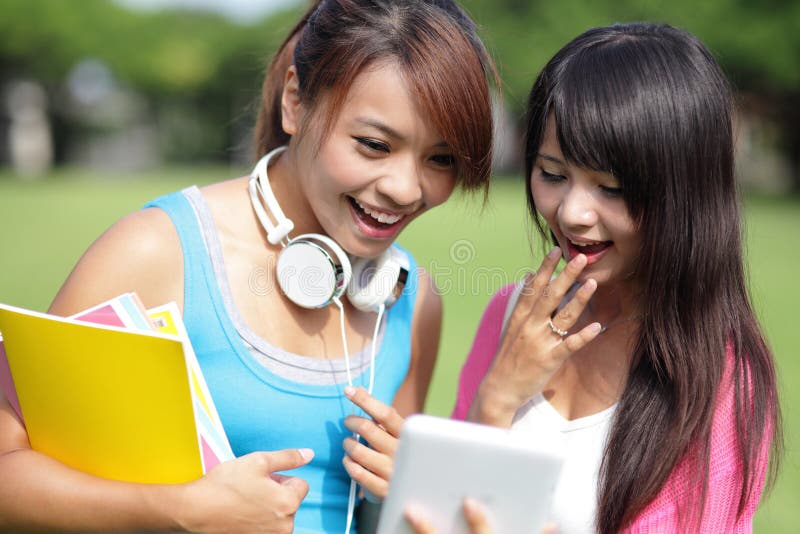 Happy girl College students smile look digital tablet pc on campus lawn, asian. Happy girl College students smile look digital tablet pc on campus lawn, asian