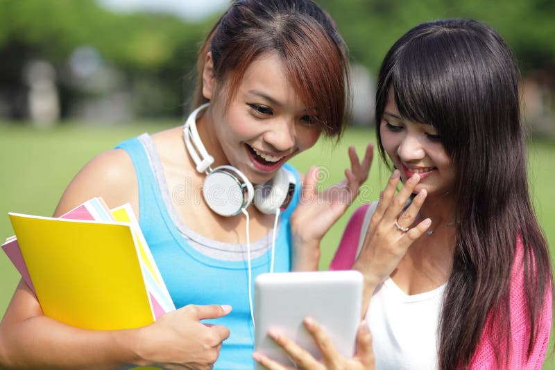 Happy girl College students smile look digital tablet pc on campus lawn, asian. Happy girl College students smile look digital tablet pc on campus lawn, asian