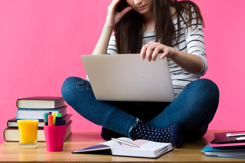 Девушка с ноутбуком на коленях Сток. Девушка изучает список на компьютере. Девушка рассматривает в спальне полу с книгами. Книги девушка учит математику.