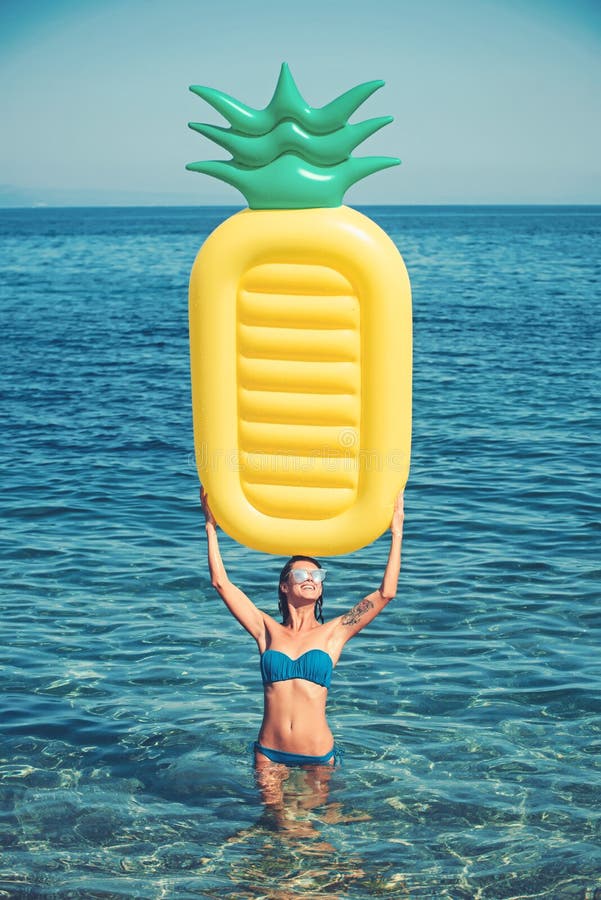 Girl sunbathing on beach with air mattress. woman on Caribbean sea in Bahamas. Pineapple inflatable mattress