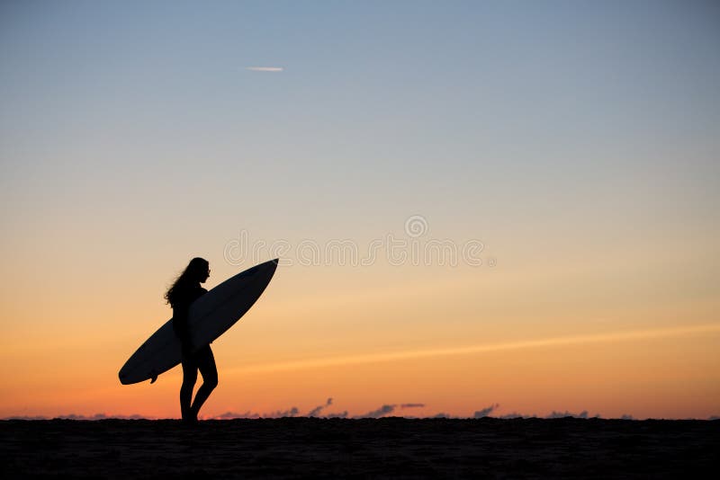 girl with surfboard in sunset at beach