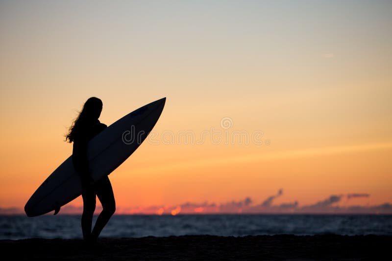 Girl with surfboard in sunset at beach