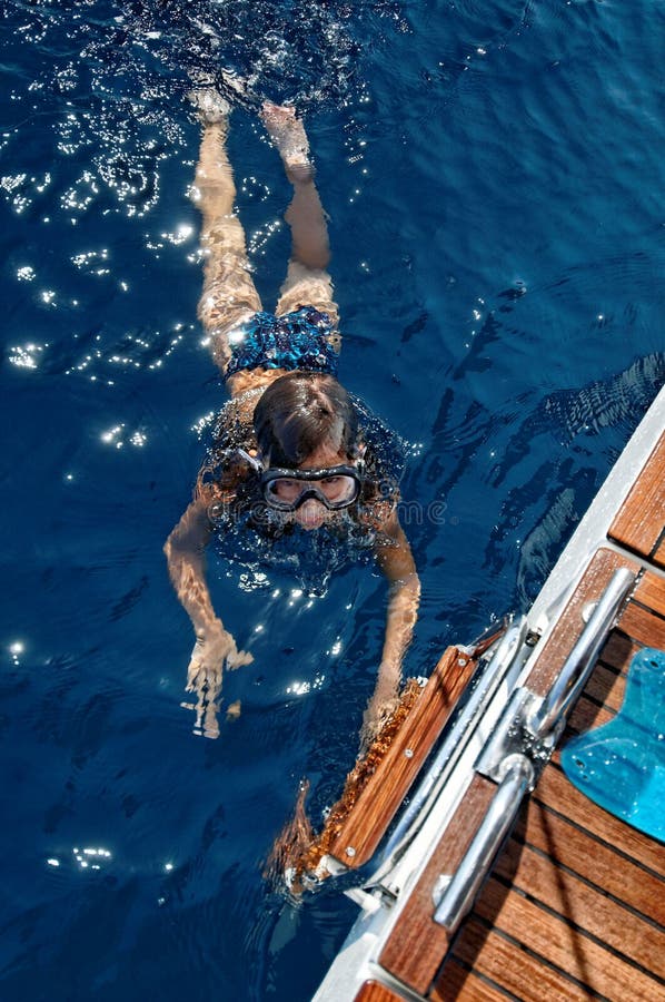 A young girl swimming and diving in sea near a boat. A young girl swimming and diving in sea near a boat.