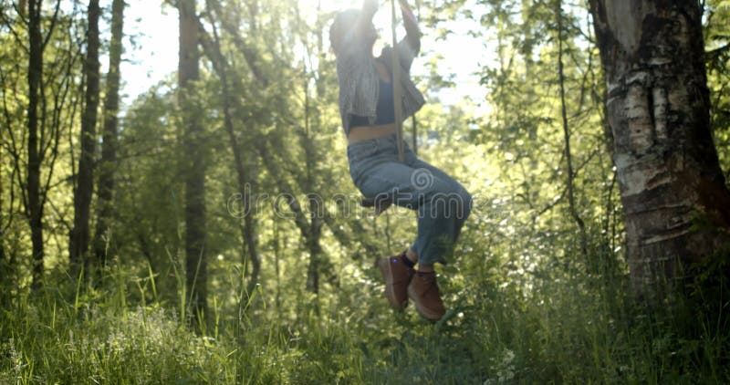 Girl swings on a bungee against the sun, happiness and joy
