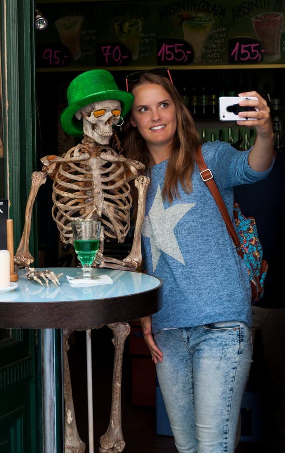 Dospievajúce dievča pričom zábavné Halloween selfie s človekom kostra predtým časté bar návštevníka.