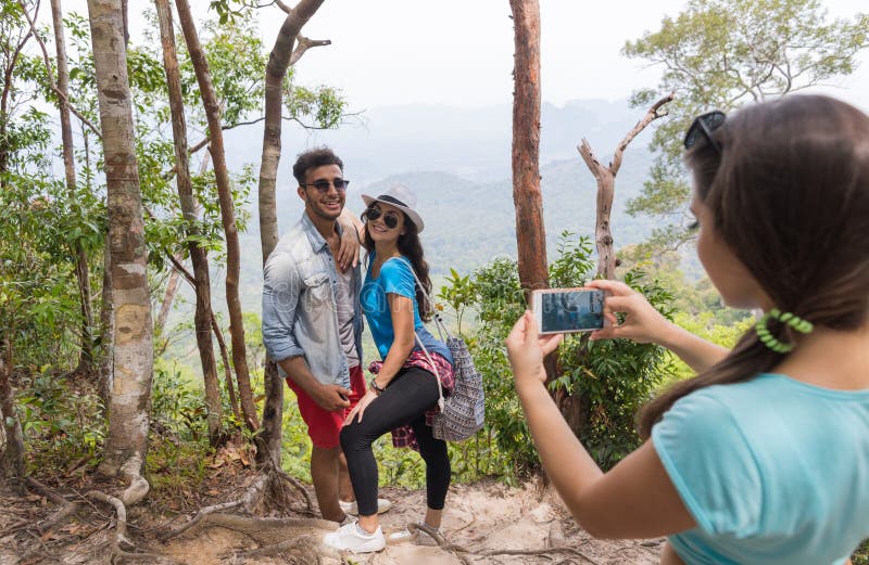 Girl Taking Photo Of Couple With Backpacks Posing Over Mountain Landscape On Cell Smart Phone, Trekking Young Man And Woman Group On Hike Tourists Adventure Activity