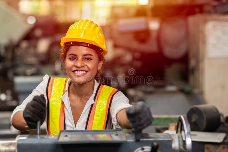 Girl teen worker with safety helmet happy smiling working labor in industry factory with steel machine stock photo