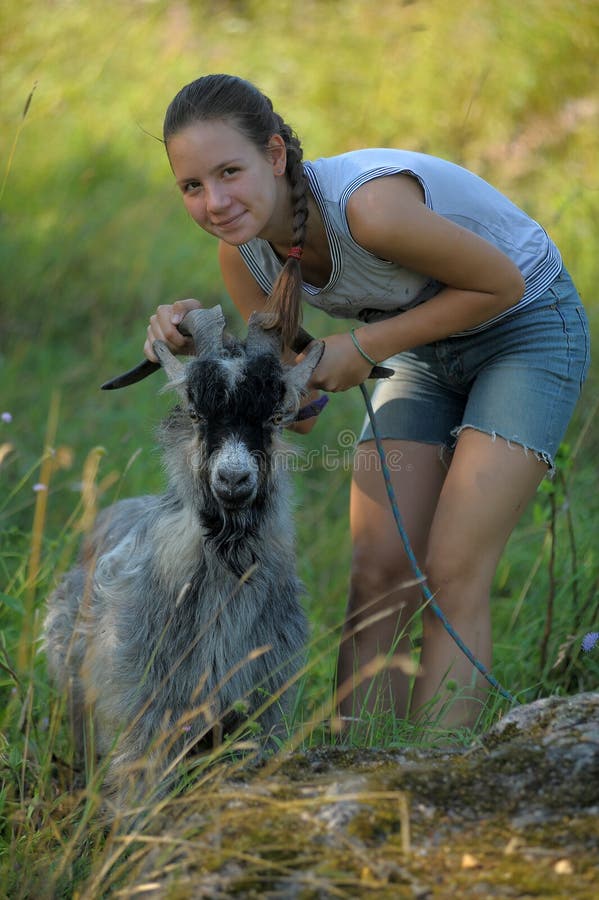 Girl teenager and a gray goat