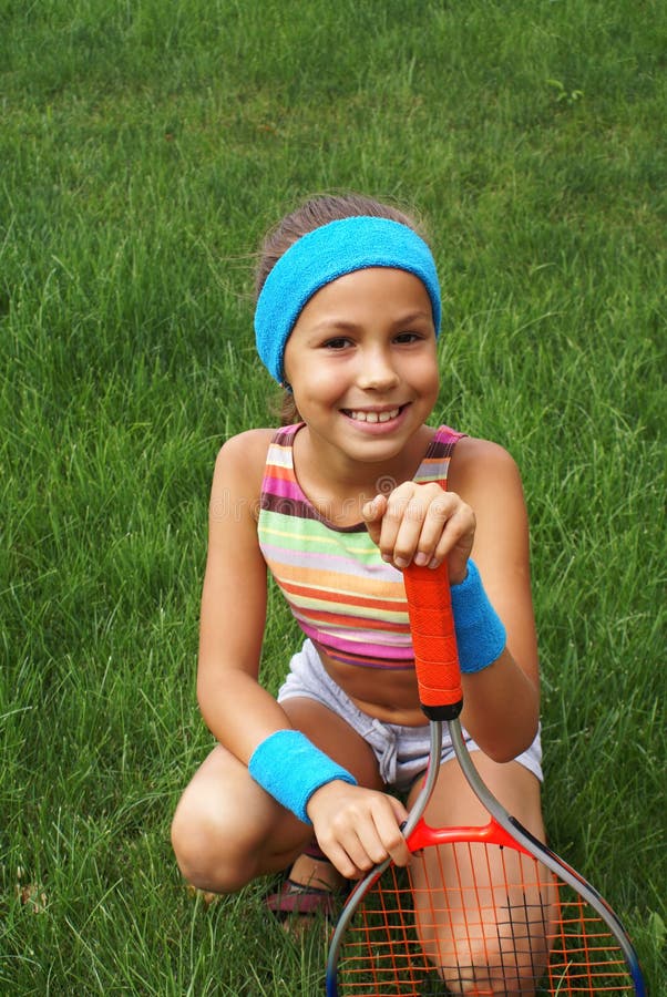 Preteen girl with tennis racket on grass background