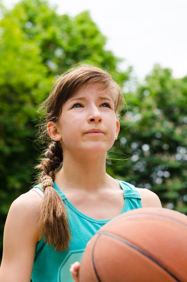 Beautiful Smiling Girl Standing with a Basketball in Outdoor Basketball