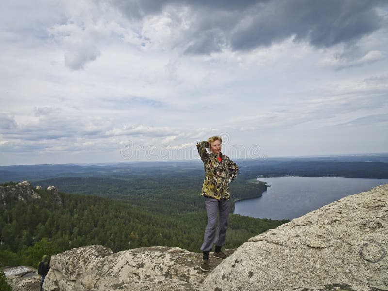 A girl on top of a mountain, in the background of a panorama of mountains and lakes. The girl is happy with height royalty free stock photography A girl on top of a mountain, in the background of a panorama of mountains and lakes. The girl is happy with height royalty free stock photography