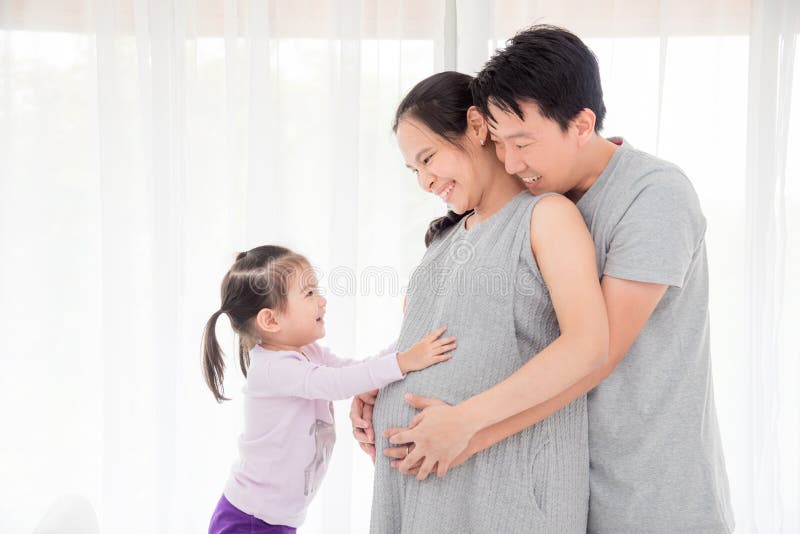 Girl touching her pregnant mother belly and smiles