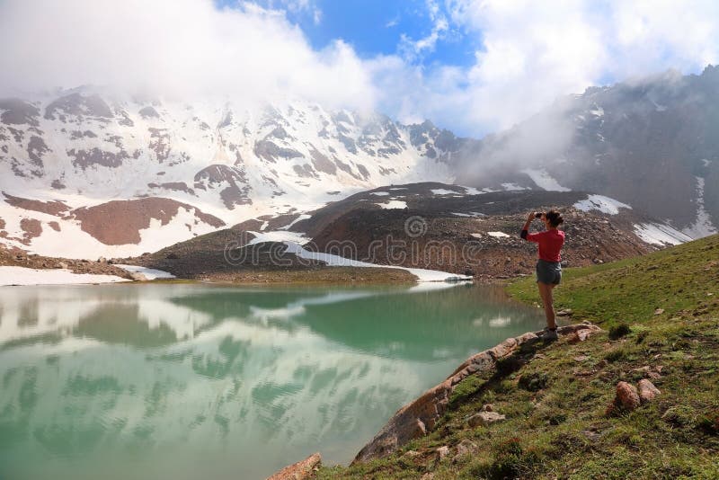 Girl tourist takes pictures on mobile phone views of the mountain lake stock photos Girl tourist takes pictures on mobile phone views of the mountain lake stock photos