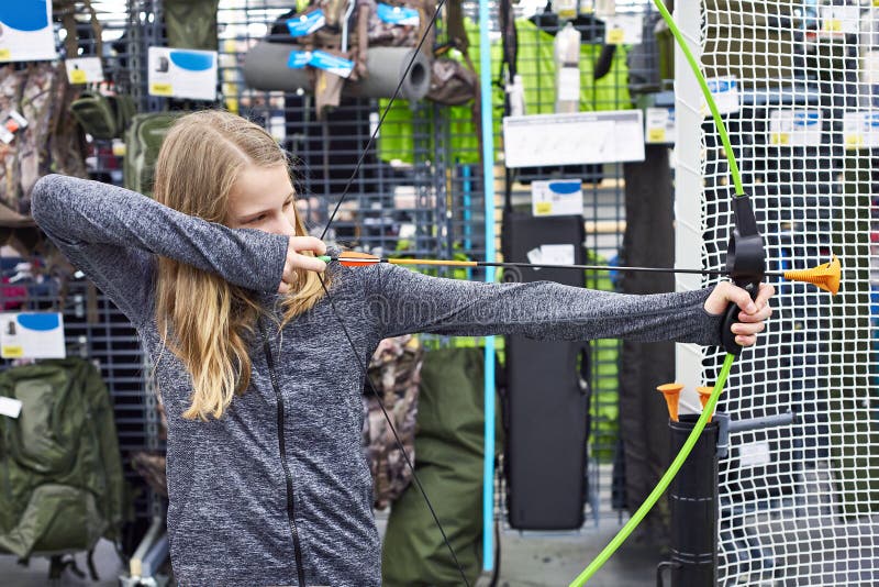 Girl is trying children`s bow in sport store