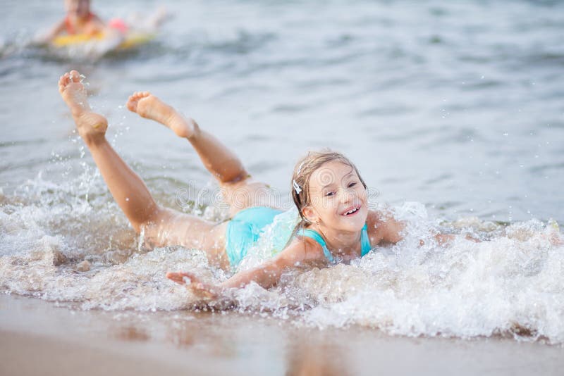 Girl in a turquoise bathing suit in the sea, happy children swimming in the sea, waves and splashes from swimming in the sea