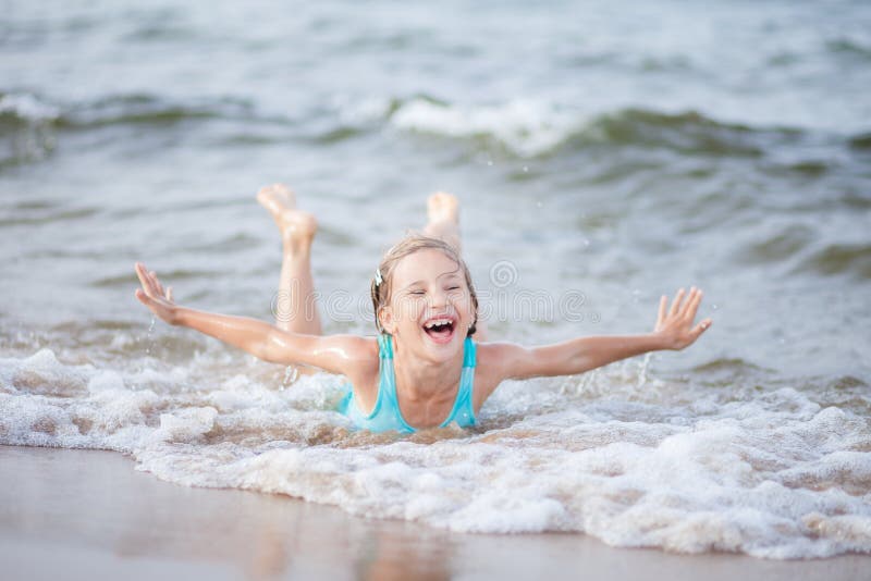 Girl in a turquoise bathing suit in the sea, happy children swimming in the sea, waves and splashes from swimming in the sea