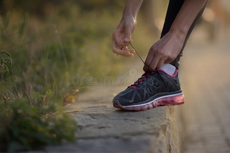 Girl tying shoelaces on running shoes for a run on the street