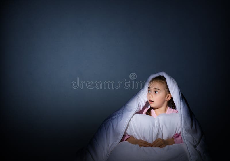 Girl under the covers with a flashlight
