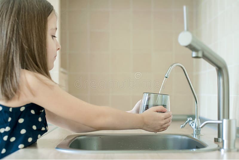 Girl using filter to purify drinking clean water. Kitchen faucet. Filling cup beverage. Infection viruses through tap water.