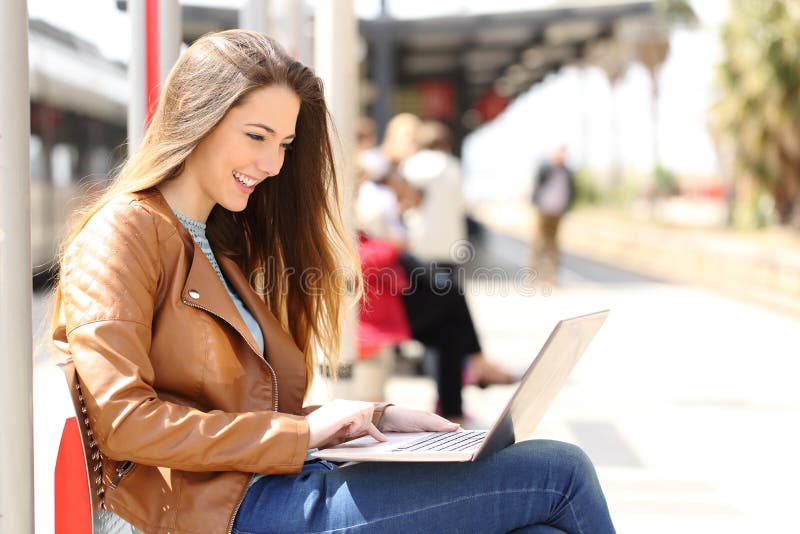 Girl using a laptop while waiting in a train station stock photography